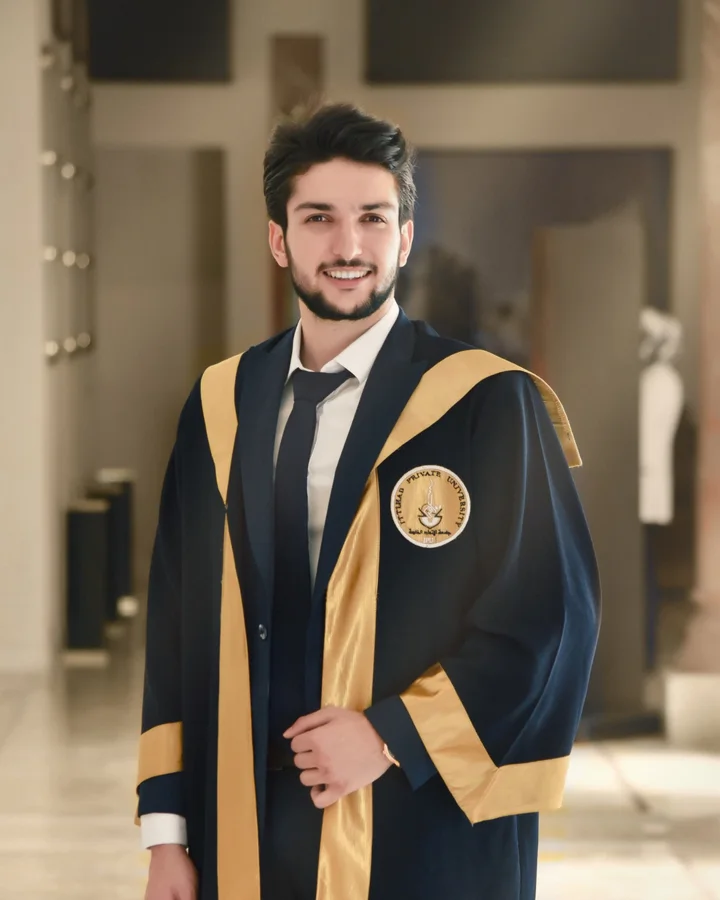 Yazan Ghajar smiling in a navy and gold graduation gown